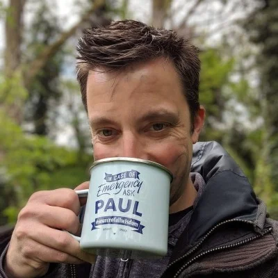 Paul Allington outdoors, holding an enamel camp mug