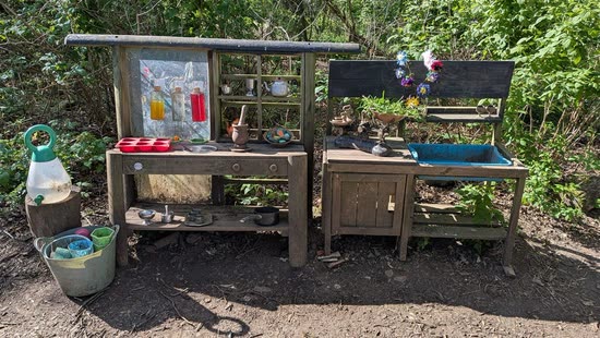 A well-used mud kitchen among the trees, pans and potion bottles ready